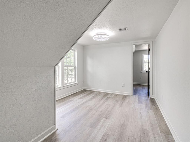 908 N Barta Ave, Prague, OK 74864 - additional living space with a textured ceiling, wood finished floors, baseboards, and a textured wall