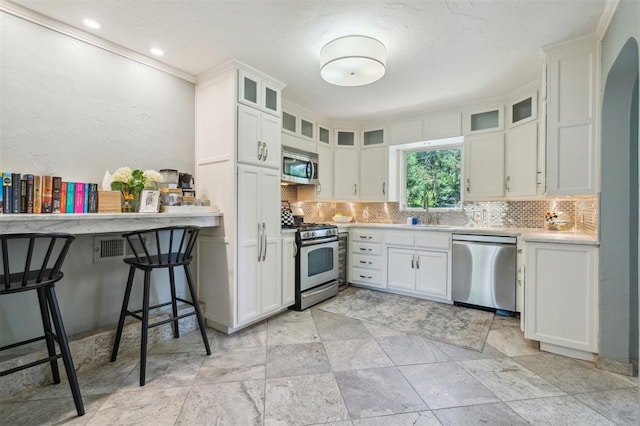 1109 Tedford Way, Nichols Hills, OK 73116 - kitchen with stainless steel appliances, decorative backsplash, light countertops, a sink, and white cabinetry