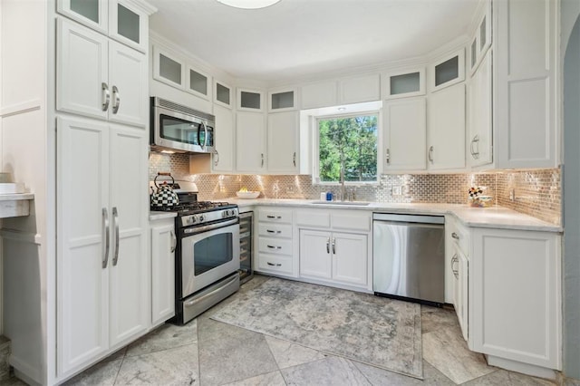 1109 Tedford Way, Nichols Hills, OK 73116 - kitchen with appliances with stainless steel finishes, a sink, decorative backsplash, white cabinetry, and glass insert cabinets