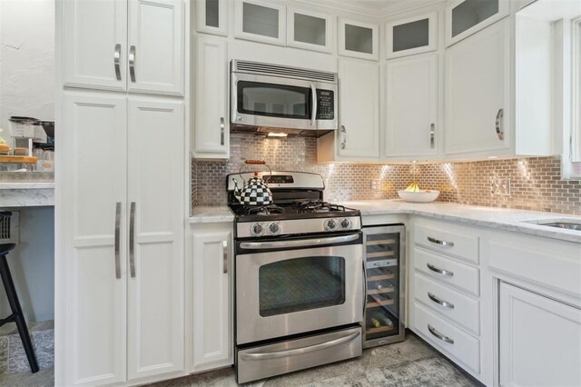 1109 Tedford Way, Nichols Hills, OK 73116 - kitchen featuring appliances with stainless steel finishes, wine cooler, white cabinets, and decorative backsplash