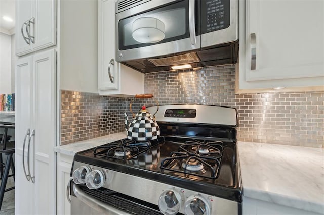1109 Tedford Way, Nichols Hills, OK 73116 - kitchen with appliances with stainless steel finishes, white cabinetry, decorative backsplash, and light stone countertops