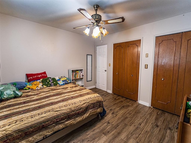 1515 S Reno Ave, El Reno, OK 73036 - bedroom featuring two closets, dark wood finished floors, baseboards, and a ceiling fan
