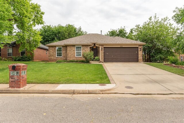 1712 De Vita Rd, Edmond, OK 73003 - view of front of home featuring a garage, a front lawn, brick siding, and driveway