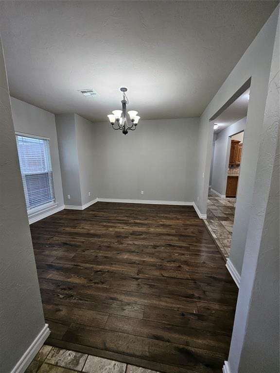1801 Caribou St, Altus, OK 73521 - spare room featuring dark wood-type flooring, a chandelier, and baseboards
