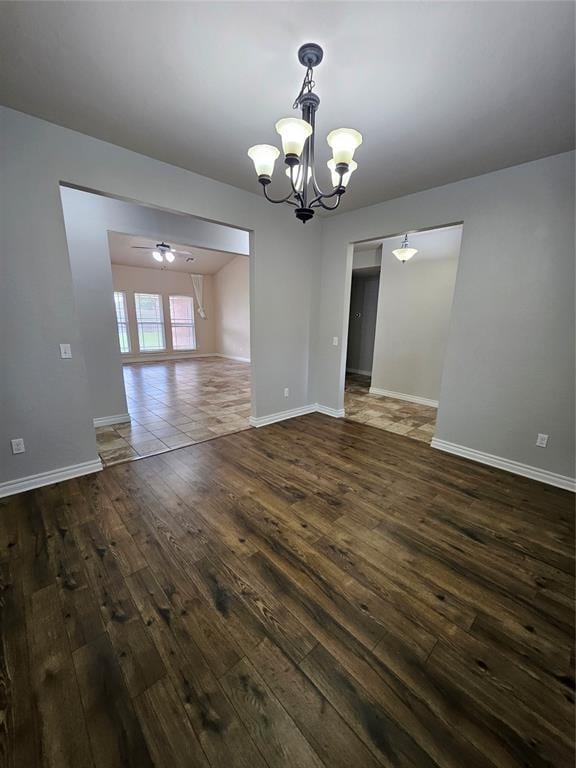 1801 Caribou St, Altus, OK 73521 - empty room featuring a chandelier, dark wood-style flooring, baseboards, and ceiling fan