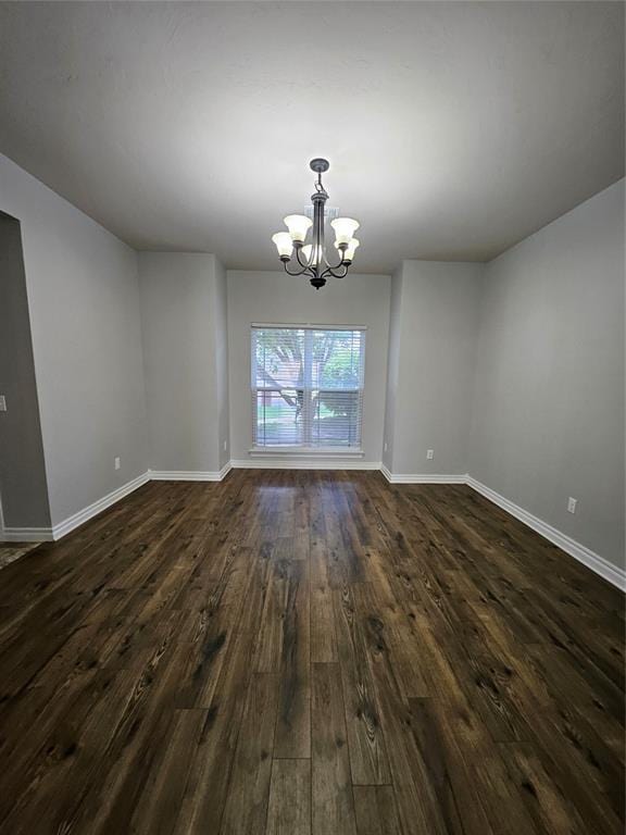 1801 Caribou St, Altus, OK 73521 - empty room with a chandelier, dark wood-type flooring, and baseboards
