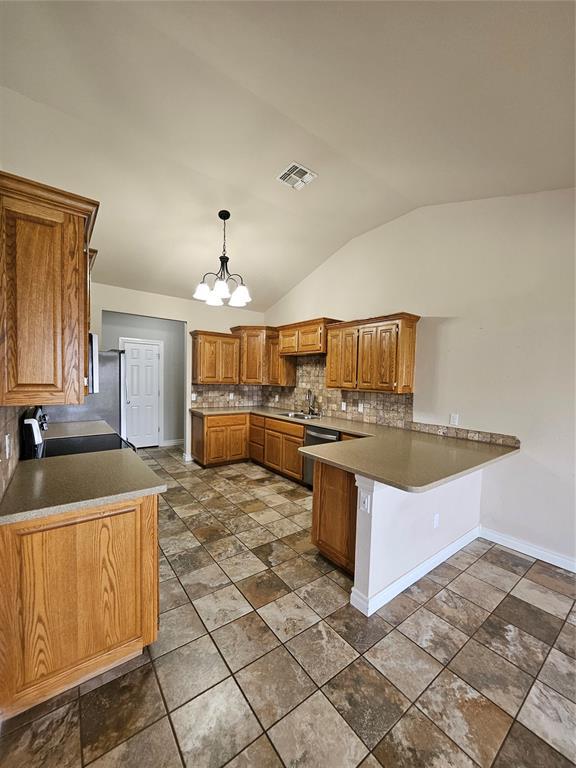 1801 Caribou St, Altus, OK 73521 - kitchen with a peninsula, vaulted ceiling, decorative backsplash, dishwasher, and brown cabinets