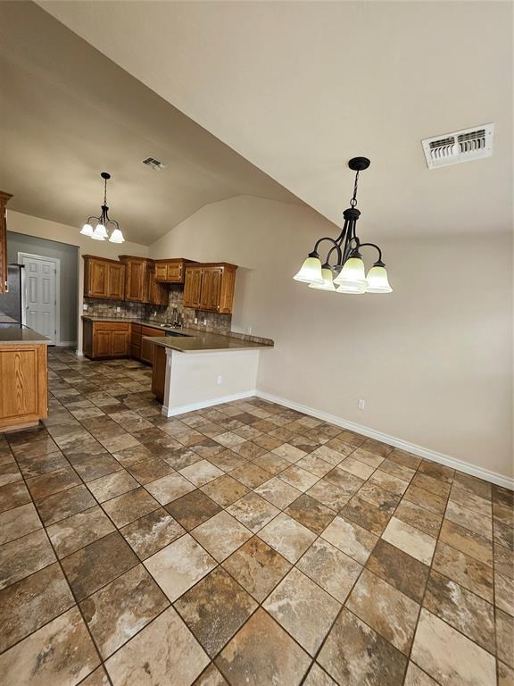 1801 Caribou St, Altus, OK 73521 - kitchen with a chandelier, a peninsula, backsplash, lofted ceiling, and hanging light fixtures