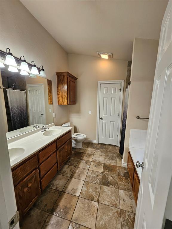 1801 Caribou St, Altus, OK 73521 - bathroom with curtained shower, double vanity, toilet, stone finish floors, and baseboards