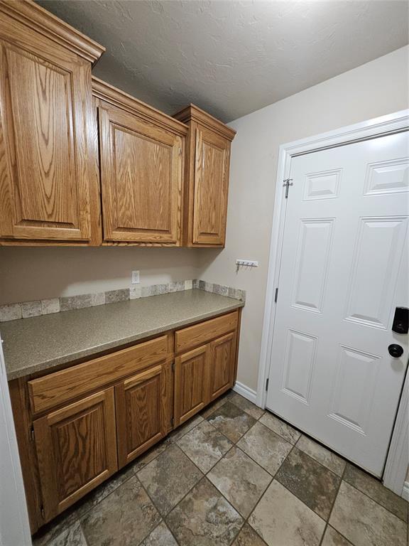 1801 Caribou St, Altus, OK 73521 - kitchen featuring dark stone finish flooring, baseboards, and brown cabinetry