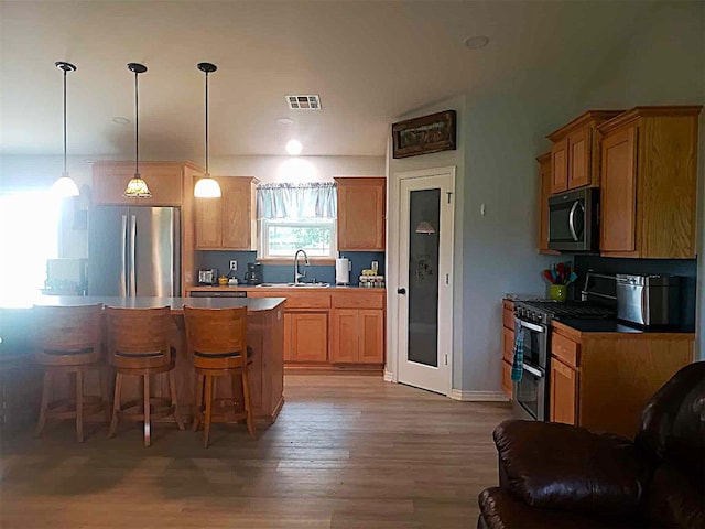 14452 Ns 3630th Rd, Sasakwa, OK 74867 - kitchen with stainless steel appliances, a sink, a breakfast bar area, light wood-style flooring, and decorative light fixtures