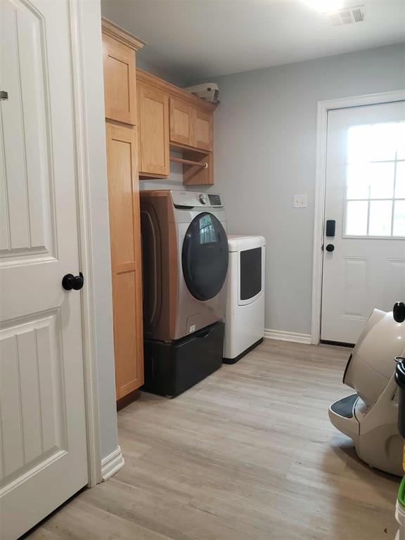 14452 Ns 3630th Rd, Sasakwa, OK 74867 - laundry room featuring washing machine and dryer, light wood-type flooring, cabinet space, and baseboards