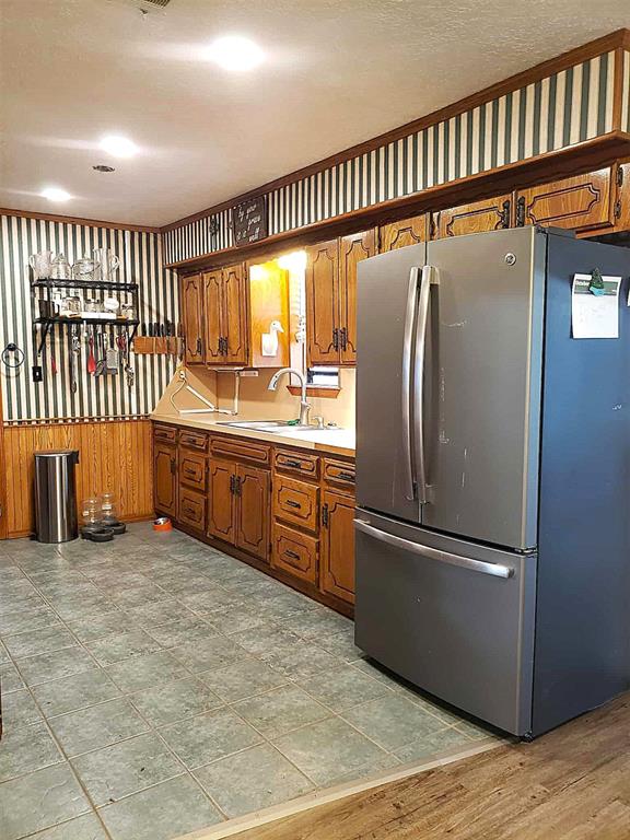 14452 Ns 3630th Rd, Sasakwa, OK 74867 - kitchen with freestanding refrigerator, a sink, brown cabinets, and light countertops