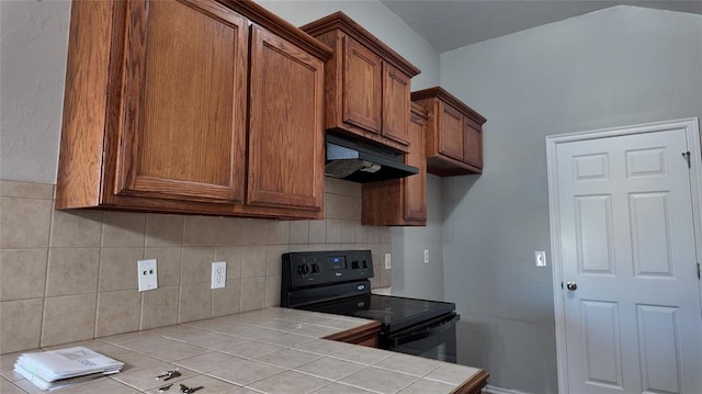 2338 Serenade Dr, Midwest City, OK 73130 - kitchen with tile countertops, custom exhaust hood, black electric range, brown cabinets, and tasteful backsplash
