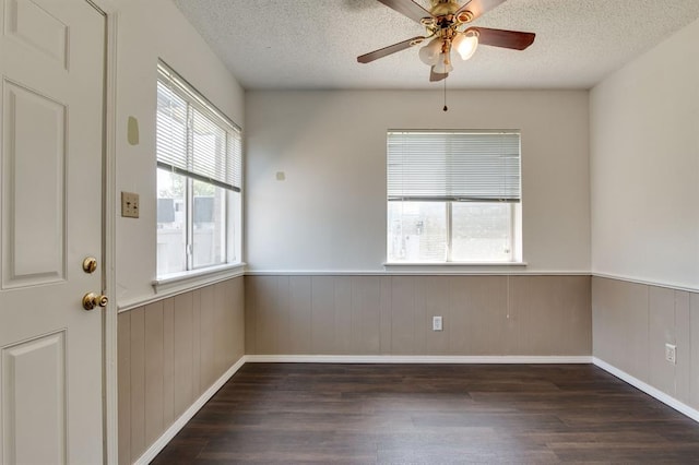 spare room featuring wood finished floors, ceiling fan, a wainscoted wall, and a textured ceiling