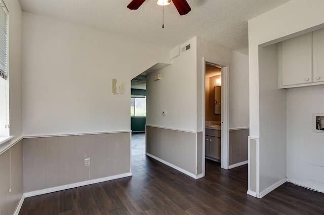 empty room with a wainscoted wall, a ceiling fan, wood finished floors, and a textured ceiling