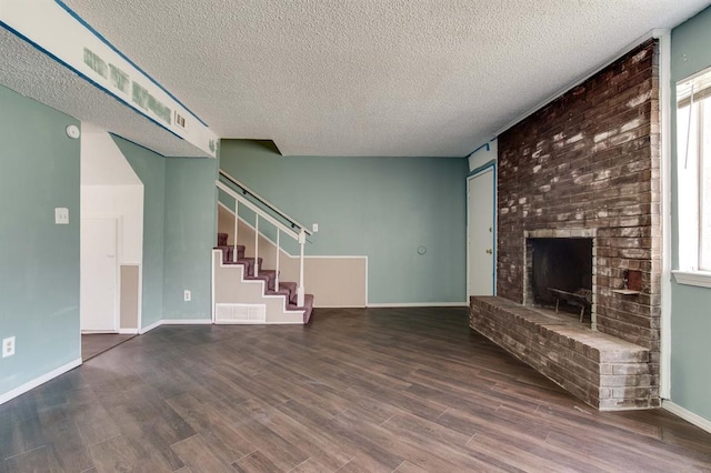 unfurnished living room featuring a textured ceiling, wood finished floors, a fireplace, stairs, and baseboards