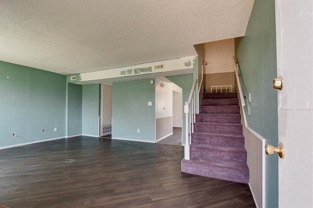stairs with a textured ceiling, wood finished floors, and baseboards