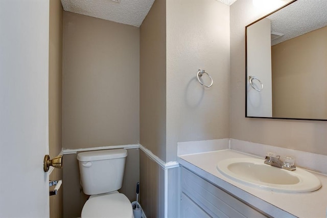 bathroom featuring a textured ceiling, toilet, and vanity