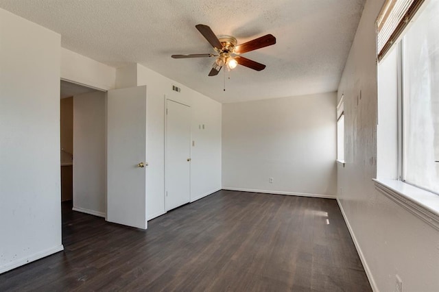 empty room featuring a ceiling fan, dark wood-style flooring, baseboards, and a textured ceiling