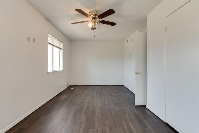 spare room featuring a ceiling fan, dark wood finished floors, baseboards, and a textured ceiling
