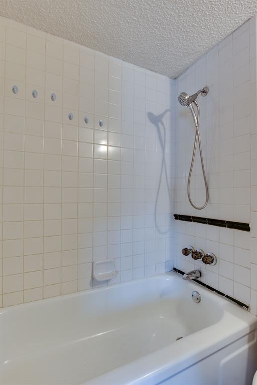 full bath featuring a textured ceiling and bathtub / shower combination