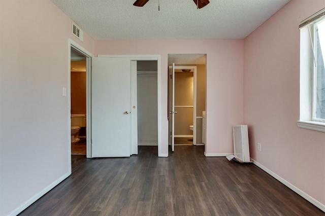unfurnished bedroom with wood finished floors, radiator, a textured ceiling, baseboards, and connected bathroom