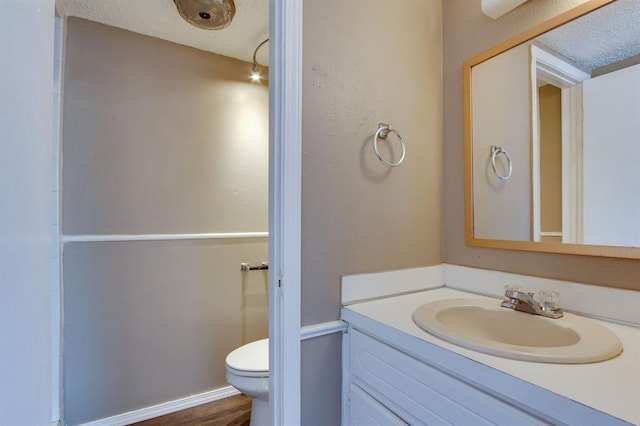 bathroom with vanity, toilet, and a textured ceiling