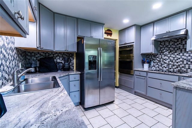 330917 E 940th Rd, Wellston, OK 74881 - kitchen with stainless steel appliances, under cabinet range hood, a sink, tasteful backsplash, and light tile patterned floors
