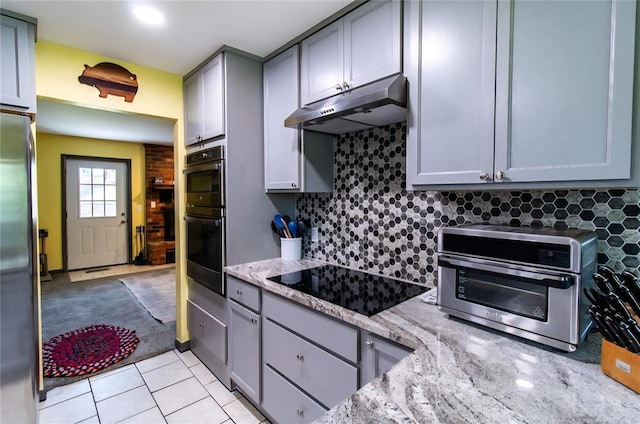 330917 E 940th Rd, Wellston, OK 74881 - kitchen with under cabinet range hood, appliances with stainless steel finishes, gray cabinetry, backsplash, and light stone countertops