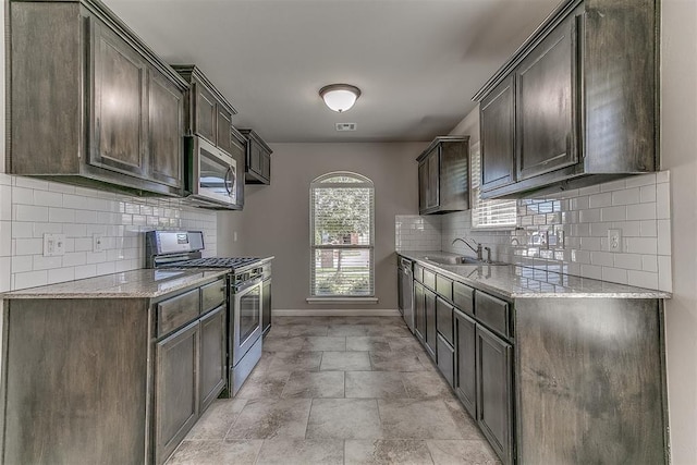4108 NW 154th St, Edmond, OK 73013 - kitchen featuring stainless steel appliances, a sink, baseboards, light stone countertops, and decorative backsplash