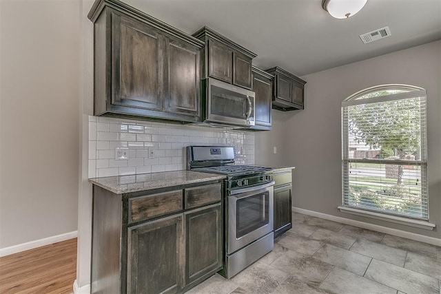 4108 NW 154th St, Edmond, OK 73013 - kitchen with appliances with stainless steel finishes, baseboards, tasteful backsplash, dark brown cabinetry, and light stone countertops