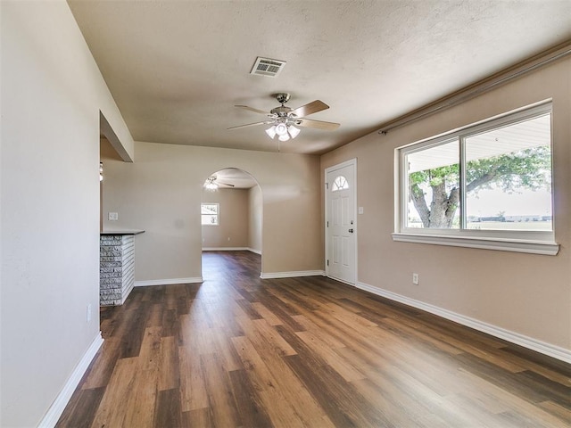 entryway featuring ceiling fan, arched walkways, wood finished floors, and baseboards