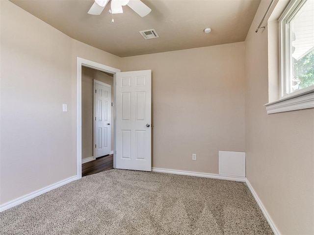 carpeted empty room featuring a ceiling fan and baseboards