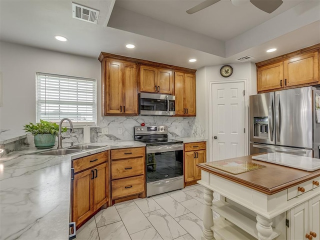1466 County Rd 1188, Tuttle, OK 73089 - kitchen featuring appliances with stainless steel finishes, recessed lighting, brown cabinetry, light marble finish flooring, and ceiling fan