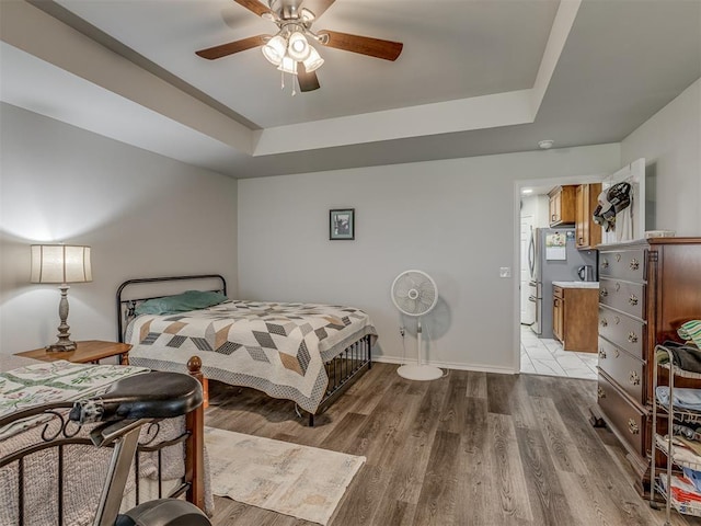 1466 County Rd 1188, Tuttle, OK 73089 - bedroom with freestanding refrigerator, a tray ceiling, light wood-style floors, and a ceiling fan