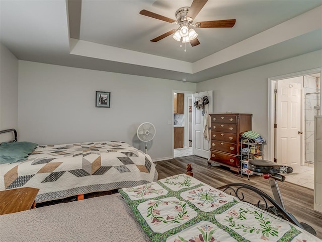 1466 County Rd 1188, Tuttle, OK 73089 - bedroom with wood finished floors, a tray ceiling, connected bathroom, and ceiling fan
