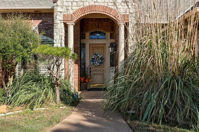 14812 Maplelake Dr, Edmond, OK 73013 - doorway to property featuring brick siding and roof with shingles