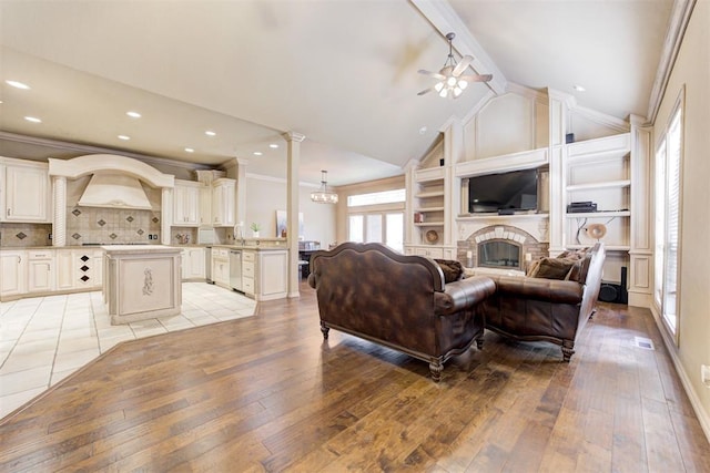 14812 Maplelake Dr, Edmond, OK 73013 - living room with light wood finished floors, a ceiling fan, a fireplace, a chandelier, and ornamental molding