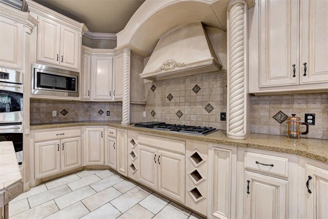 14812 Maplelake Dr, Edmond, OK 73013 - kitchen featuring appliances with stainless steel finishes, custom exhaust hood, light tile patterned floors, and backsplash