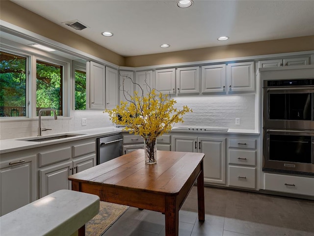 2901 NE 122nd St, Edmond, OK 73013 - kitchen featuring stainless steel appliances, a sink, light countertops, tile patterned flooring, and tasteful backsplash