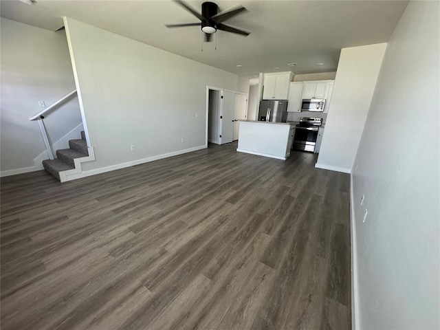 1867 Comice Dr, Newcastle, OK 73065 - unfurnished living room with a ceiling fan, dark wood-style flooring, stairs, and baseboards