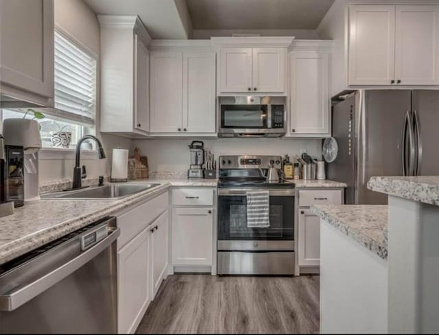 1867 Comice Dr, Newcastle, OK 73065 - kitchen featuring stainless steel appliances, a sink, light wood-style flooring, and white cabinetry