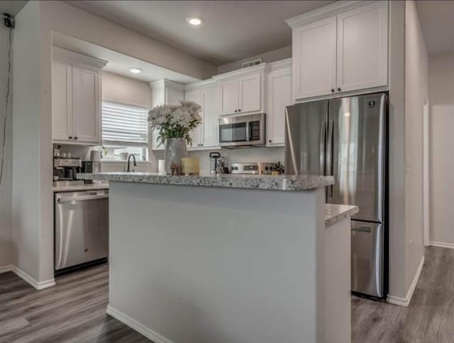 1867 Comice Dr, Newcastle, OK 73065 - kitchen with appliances with stainless steel finishes, baseboards, a kitchen island, dark wood-type flooring, and white cabinetry