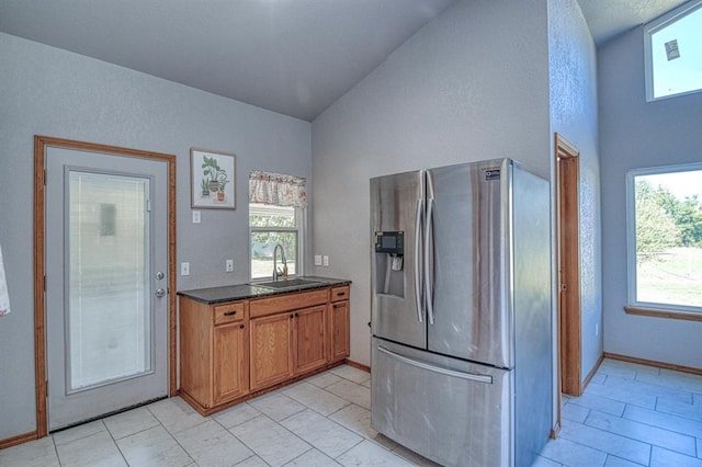 4419 SE 57th St, Del City, OK 73135 - kitchen with stainless steel refrigerator with ice dispenser, a sink, brown cabinets, high vaulted ceiling, and baseboards
