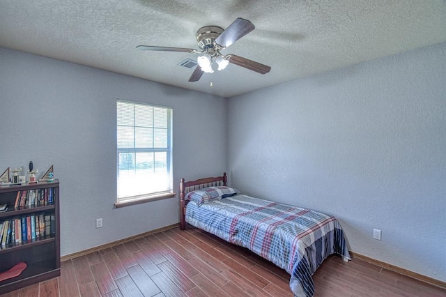 4419 SE 57th St, Del City, OK 73135 - bedroom featuring wood finished floors, a textured wall, baseboards, a textured ceiling, and ceiling fan
