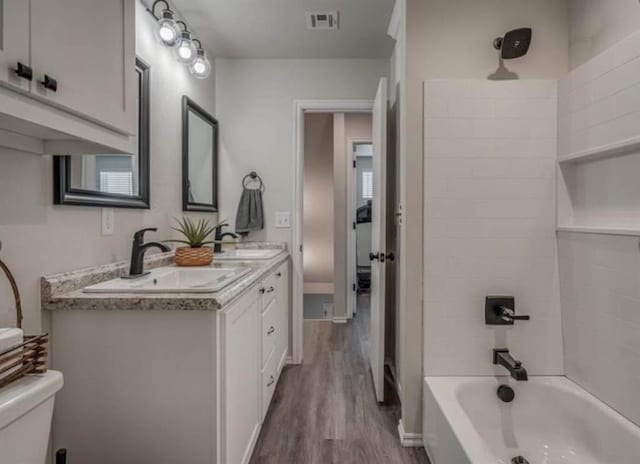 1663 Comice Dr, Newcastle, OK 73065 - full bathroom with wood finished floors, toilet, double vanity, and washtub / shower combination