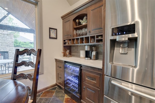 7616 NW 134th St, Oklahoma City, OK 73142 - indoor dry bar with stainless steel refrigerator with ice dispenser, wine cooler, baseboards, stone tile flooring, and lofted ceiling