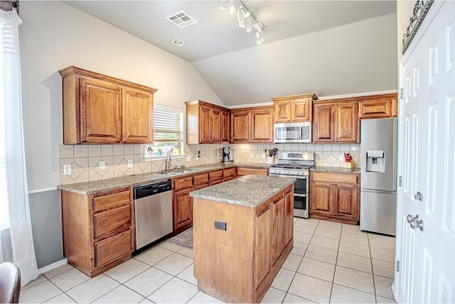 708 Ashwood Ln, Moore, OK 73160 - kitchen with stainless steel appliances, a sink, light tile patterned flooring, a kitchen island, and vaulted ceiling