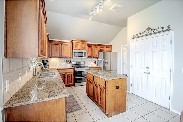 708 Ashwood Ln, Moore, OK 73160 - kitchen featuring appliances with stainless steel finishes, a sink, backsplash, track lighting, and a kitchen island